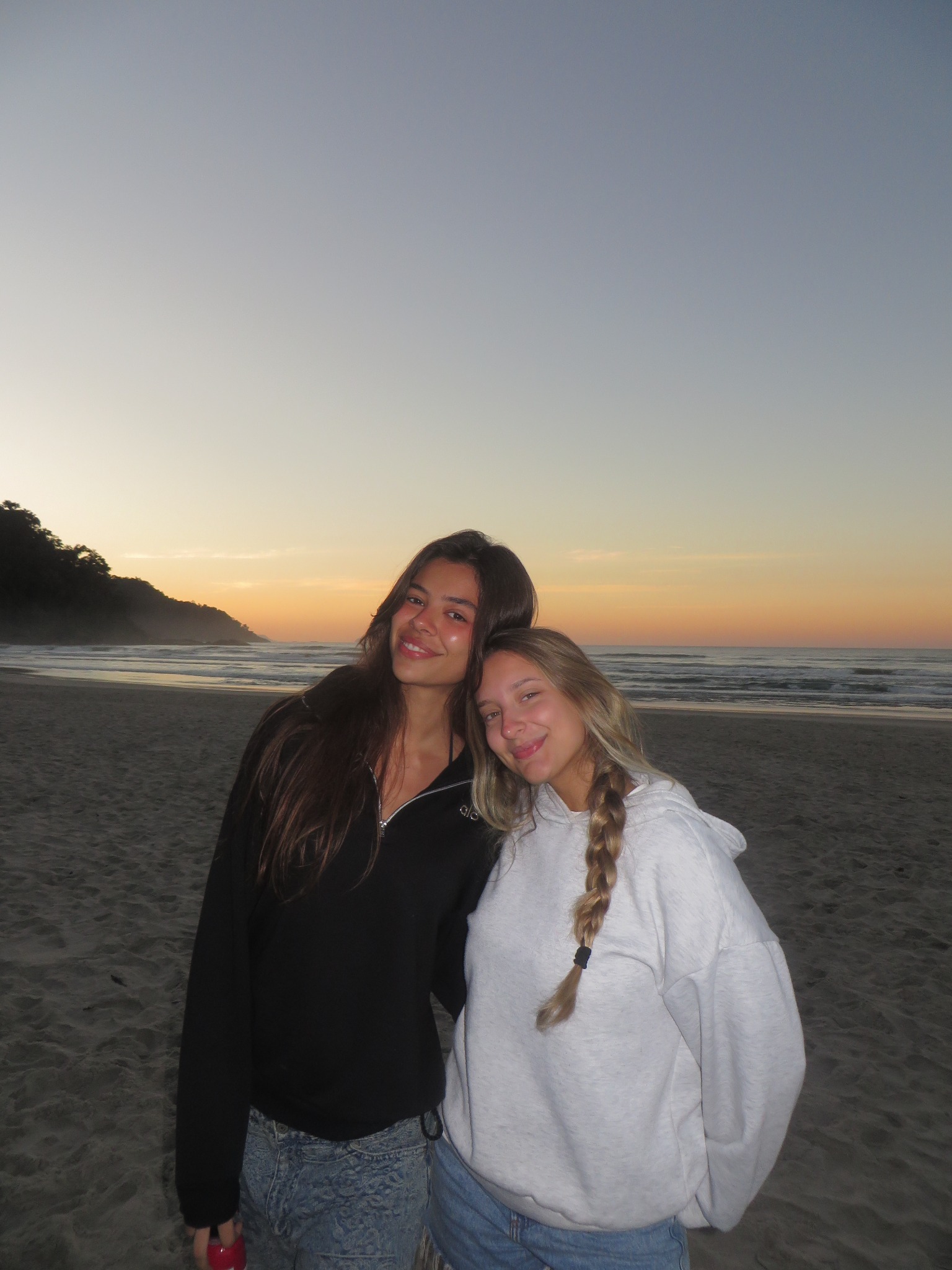 Amigas na praia ao pôr do sol