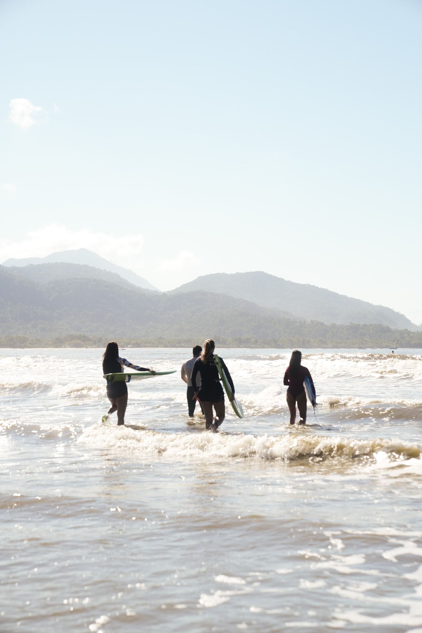 Grupo entrando no mar com pranchas de surf